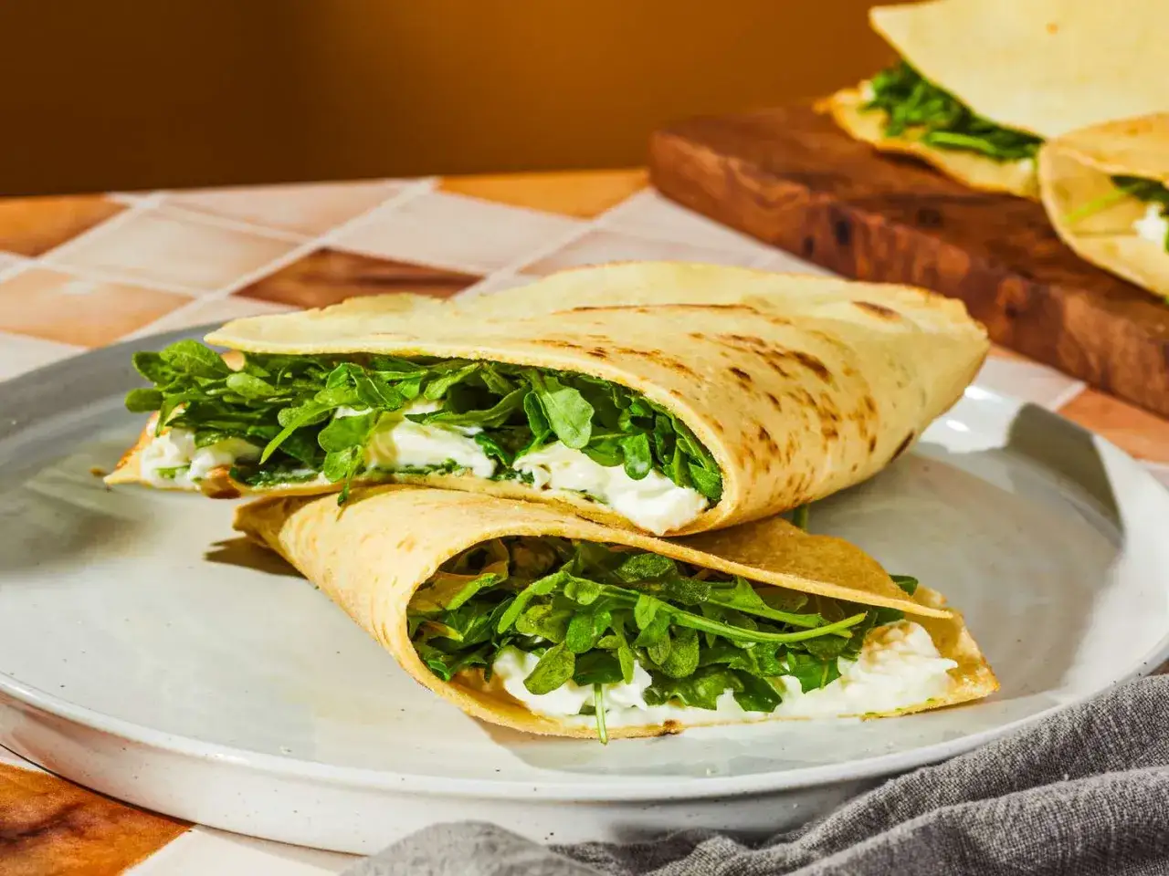 Två halvor av en piadina med krämig ost och ruccola. Ett enkelt piadina recept för en snabb och god lunch.