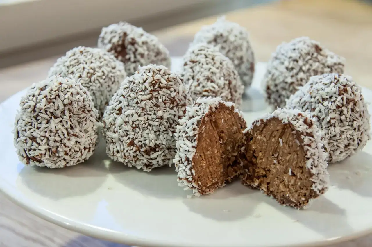 En hög med chokladbollar, rullade i kokos. Ett enkelt och gott delicatobollar recept som passar alla.