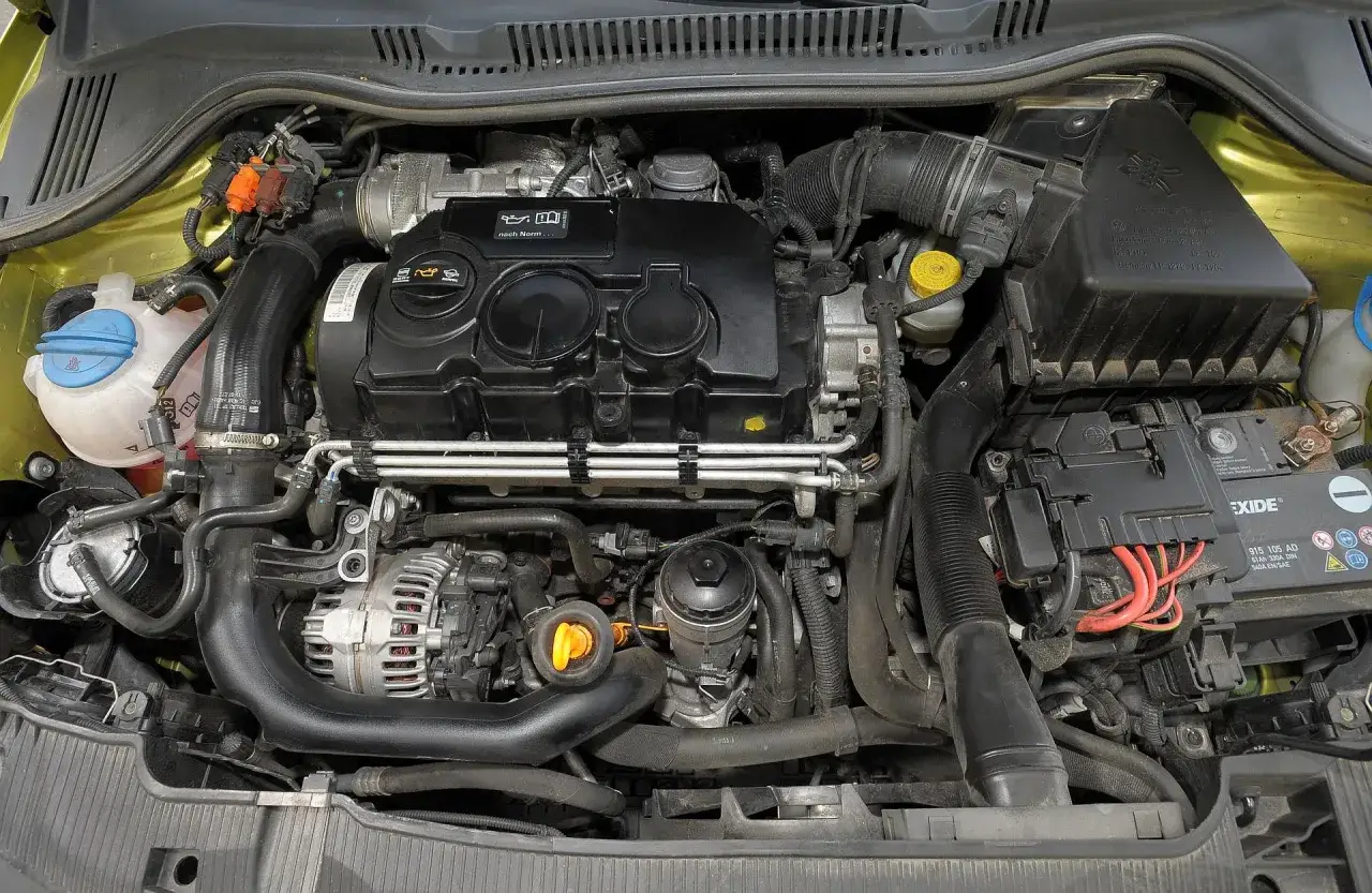 Silnik 1.4 benzyna w Seat Ibiza. Widoczny alternator, akumulator Exide, obudowa filtra powietrza i elementy układu dolotowego.