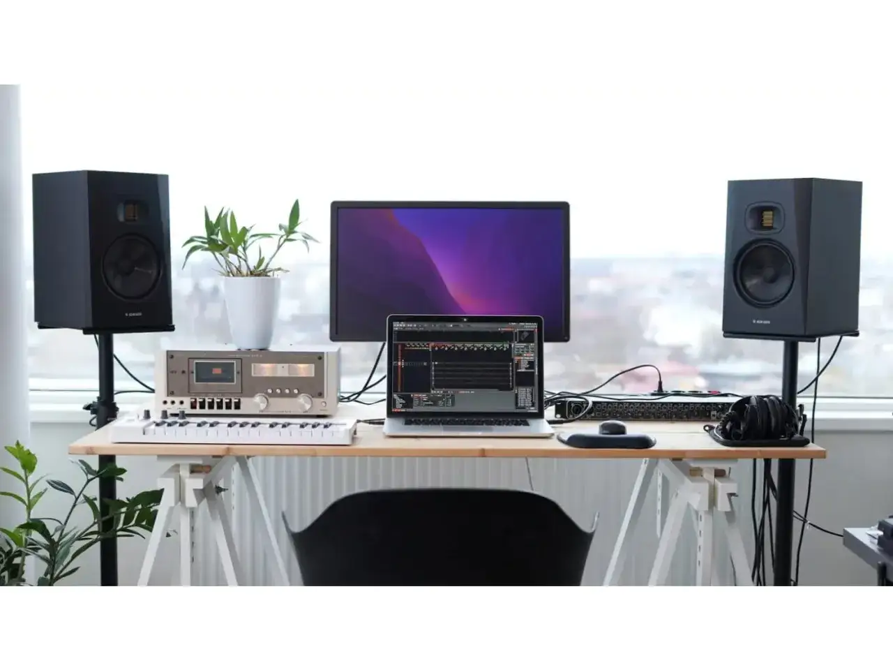 Studio z monitorami Adam Audio T7V, laptopem, klawiaturą i sprzętem audio.