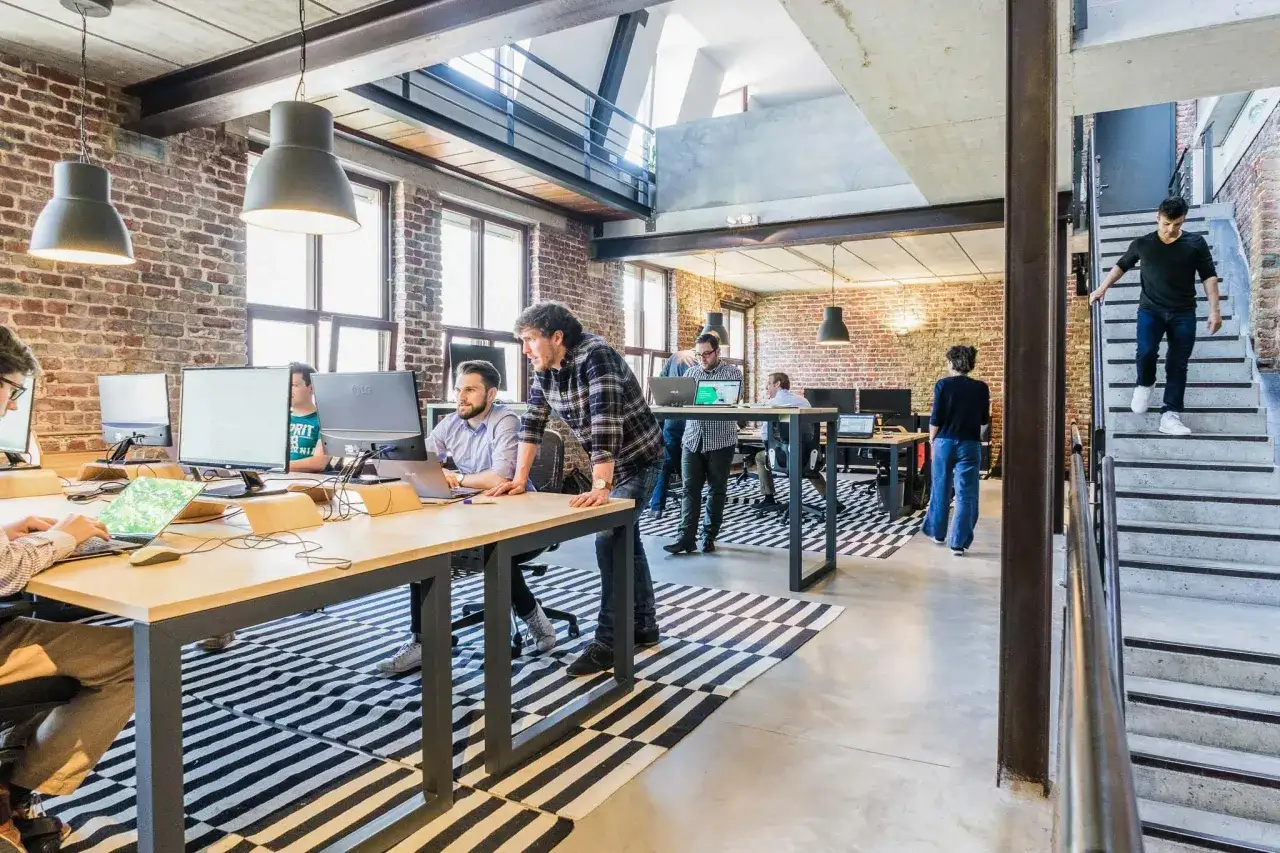 Ambiance dynamique pour travailler dans une start up : des employés concentrés sur leurs écrans, un homme descendant les escaliers.