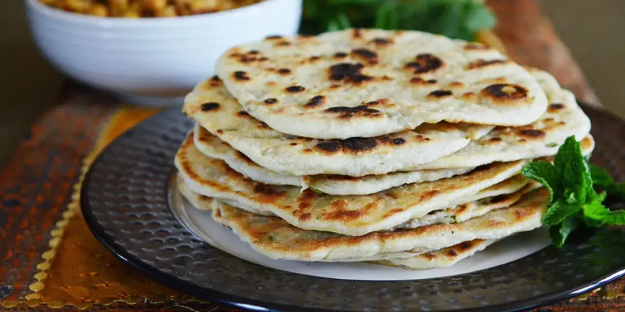 Ein Stapel frisch gebackenes indisches Fladenbrot, leicht gebr&auml;unt und mit Minze garniert, bereit zum Genie&szlig;en.