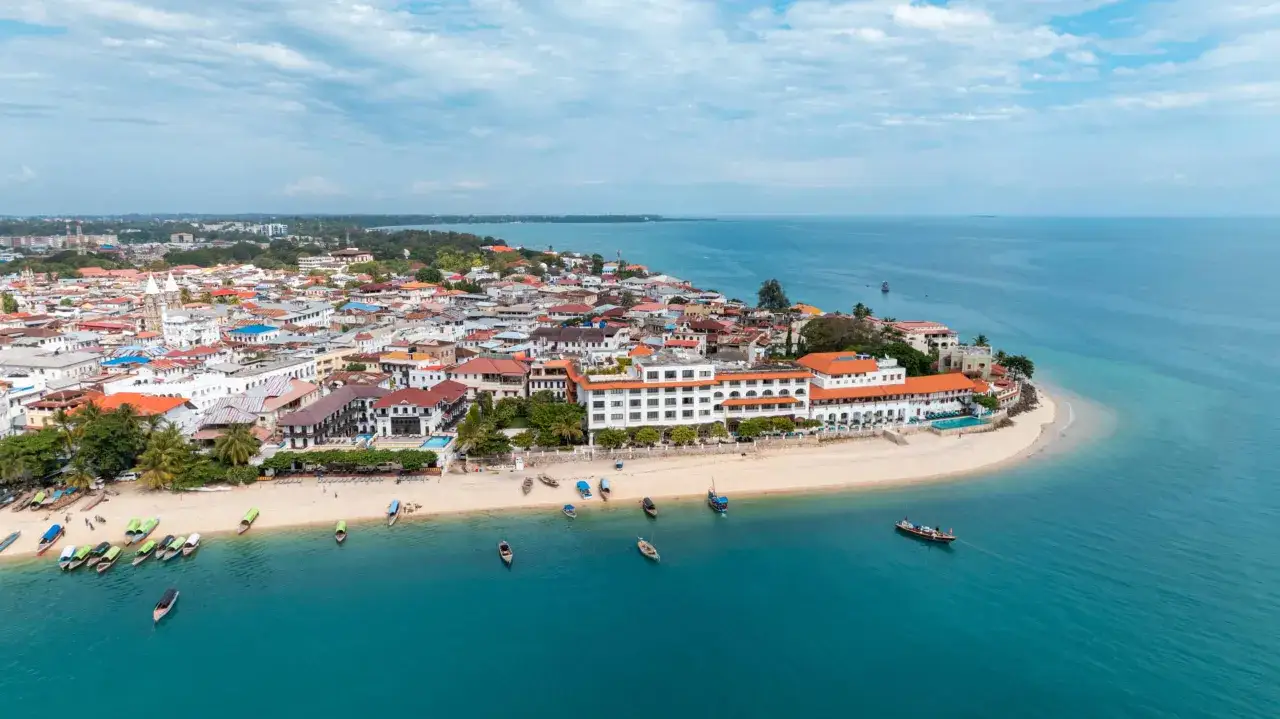 Zanzibar co warto wiedzieć: malownicze wybrzeże z kamiennymi domami Stone Town, plaża z łodziami i turkusowe morze.