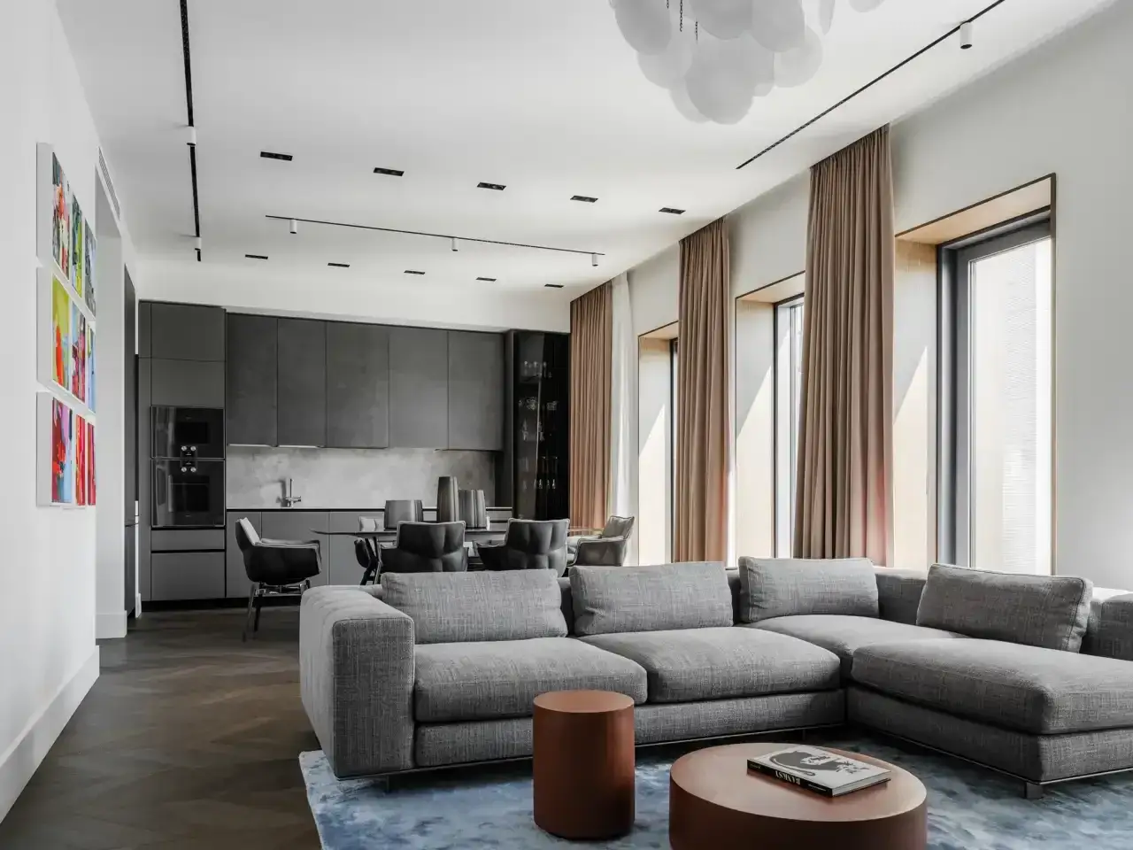 Elegante salón-comedor con sofás grises y cocina moderna. Los **tonos grises para paredes interiores** crean un ambiente sofisticado y sereno.