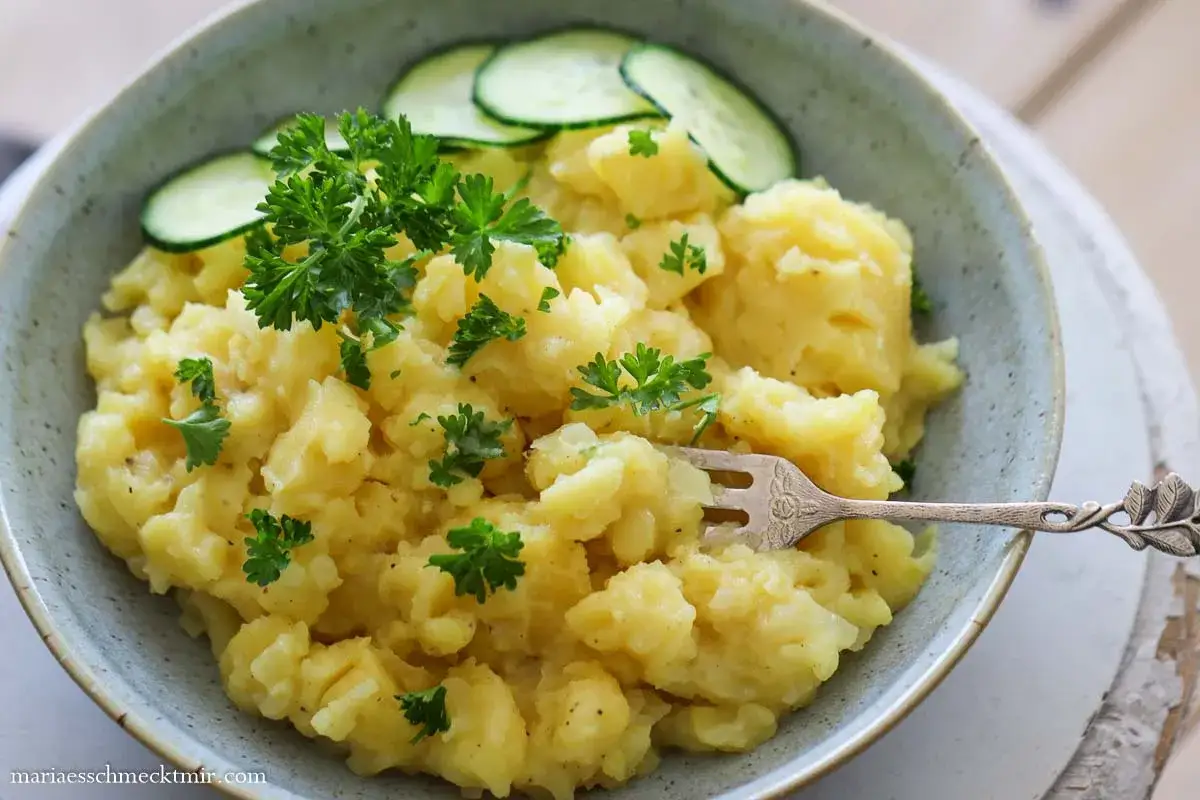 Ein cremiger Kartoffelsalat, garniert mit Petersilie und Gurkenscheiben. Das ist das Kartoffelsalat Geheimrezept, das jeder lieben wird!