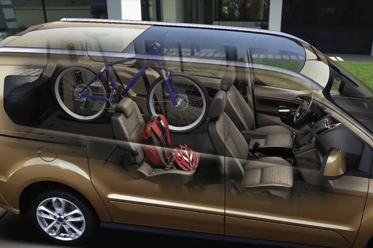 Interior de una camioneta dorada con una bicicleta azul y cascos rojos. ¡Perfecto para evitar la multa por llevar bici dentro del coche!