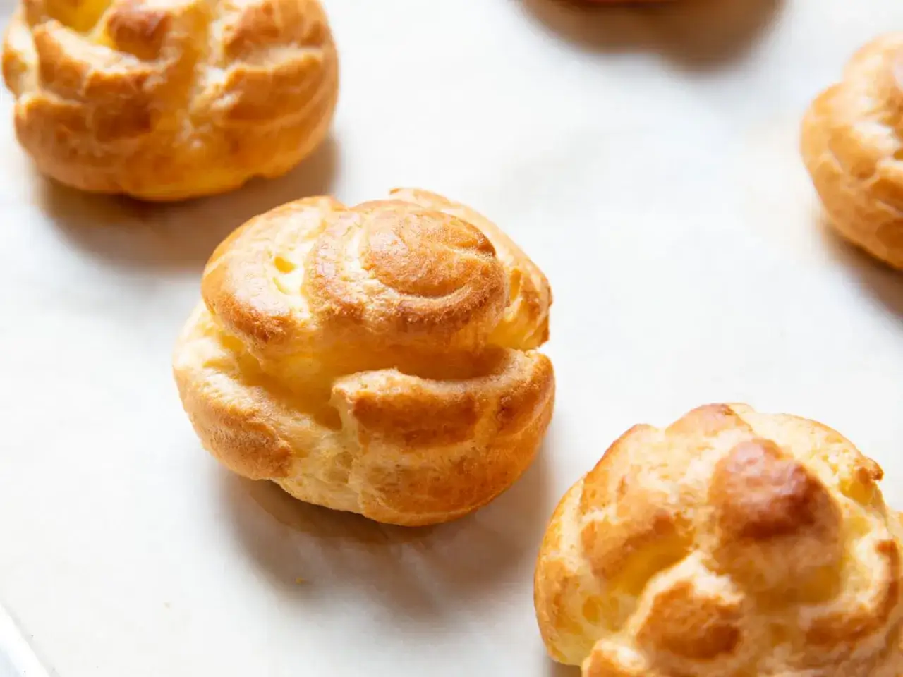 Petits choux dor&eacute;s, pr&ecirc;ts &agrave; &ecirc;tre garnir. Une &eacute;tape cl&eacute; de la recette p&acirc;te &agrave; choux pour des desserts l&eacute;gers et a&eacute;riens.