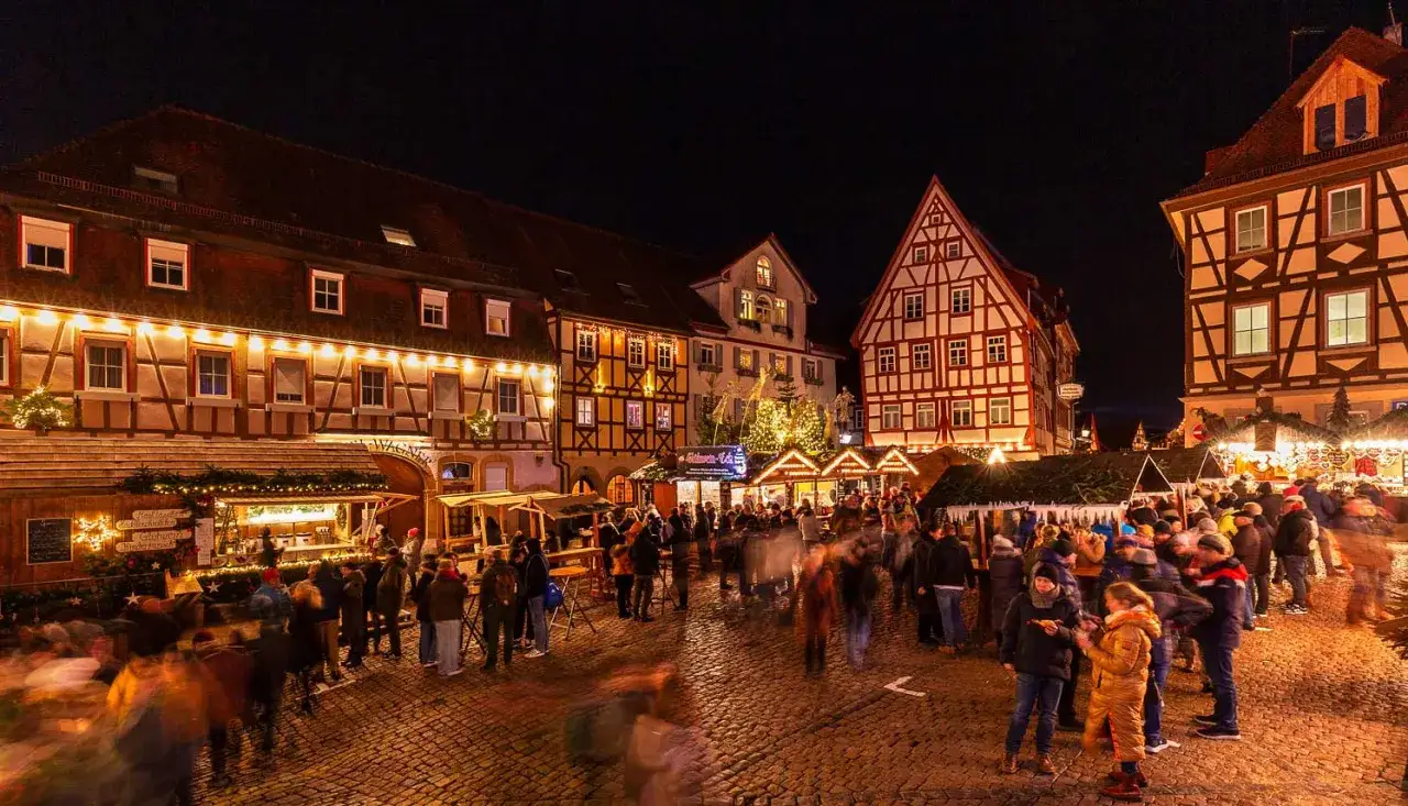 Bunte Lichter und gesch&auml;ftiges Treiben auf dem **Bad Wimpfen Weihnachtsmarkt**. Fachwerkh&auml;user und Buden laden zum Verweilen ein.