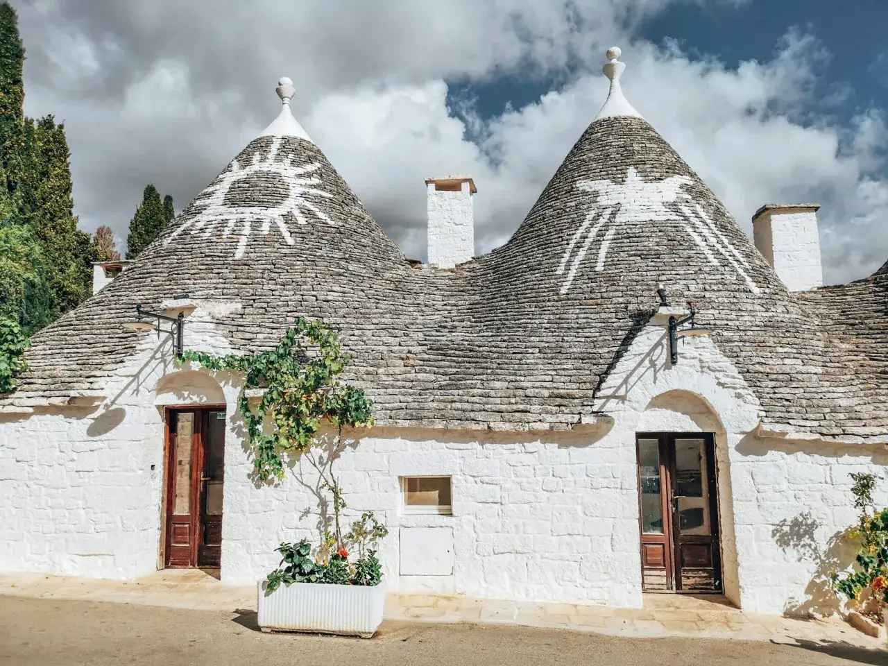 Urocze trulli w Alberobello, z kamiennymi dachami i białymi ścianami, ozdobione symbolami słońca.