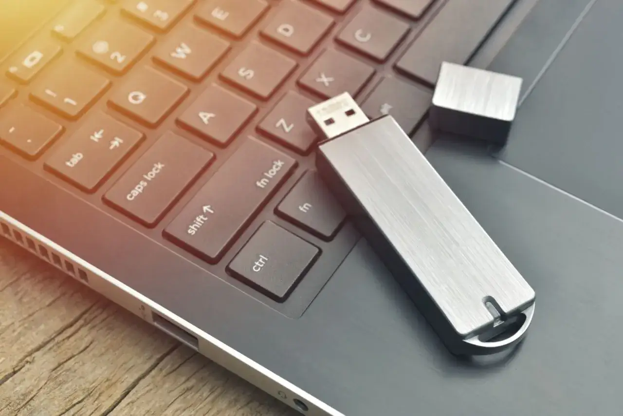 USB-Stick reparieren mit CMD: Ein silberner USB-Stick liegt auf einer Laptop-Tastatur.