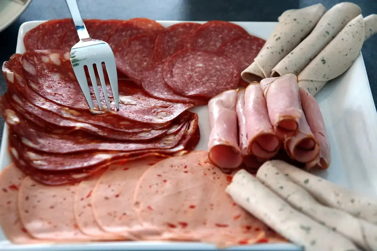 Talerz z wędlinami: salami, szynka, kiełbasa. Wskazówka, jak przechowywać wędlinę w lodówce, by była świeża.