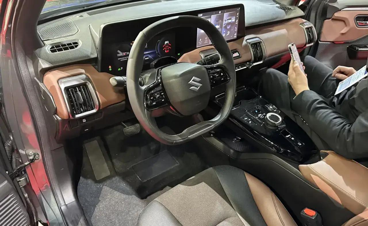 Wnętrze Suzuki Vitara z brązowymi akcentami, nowoczesnym ekranem i kierownicą.