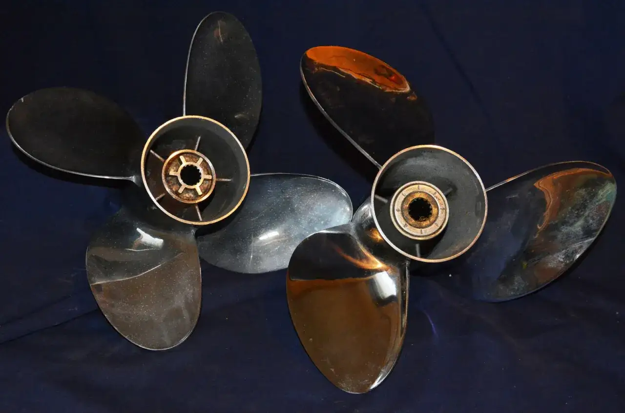 Zwei glänzende 4-Blatt-Propeller liegen nebeneinander auf dunkelblauem Stoff.