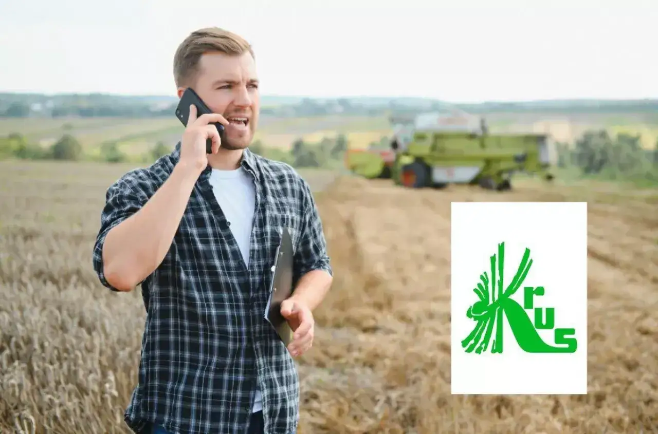 Rolnik aktywny zawodowo rozmawia przez telefon na polu podczas żniw. W tle kombajn.