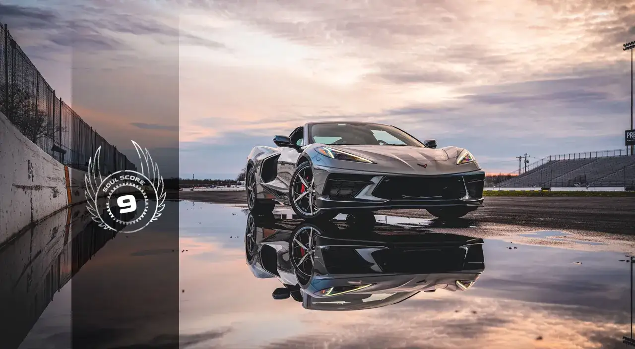 Szary Corvette Stingray odbija się w mokrej nawierzchni toru wyścigowego.