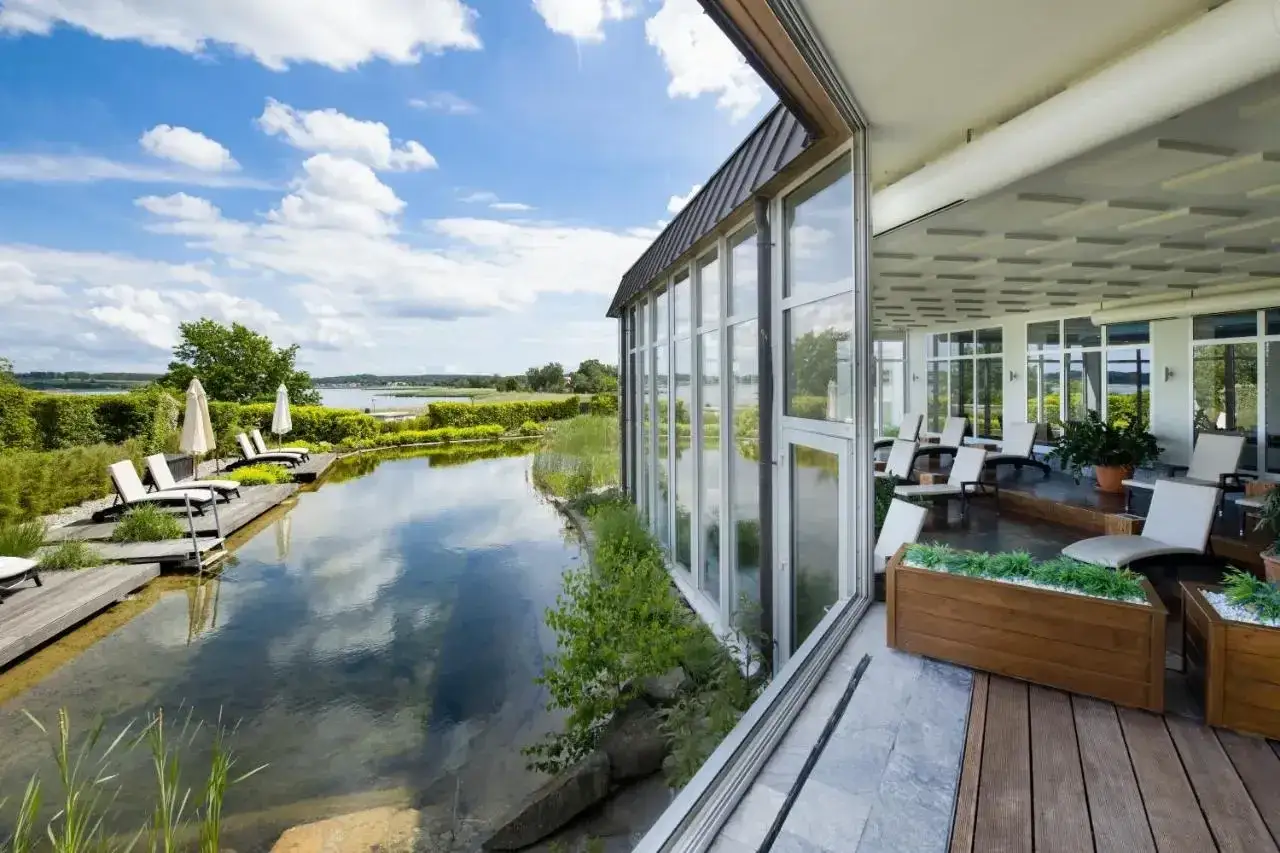 Entspannung pur in einem der besonderen Hotels Norddeutschland. Ein Naturpool lädt zum Verweilen ein, während die Glasfronten den Blick auf die idyllische Landschaft freigeben.