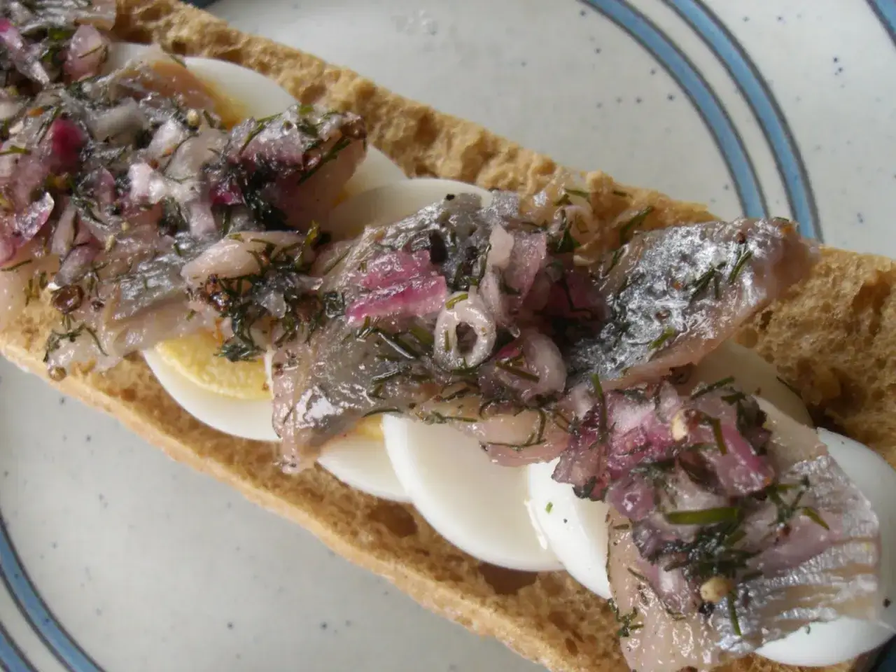 En smörgås med sill, ägg och rödlök, som påminner om ett brantevikssill recept.