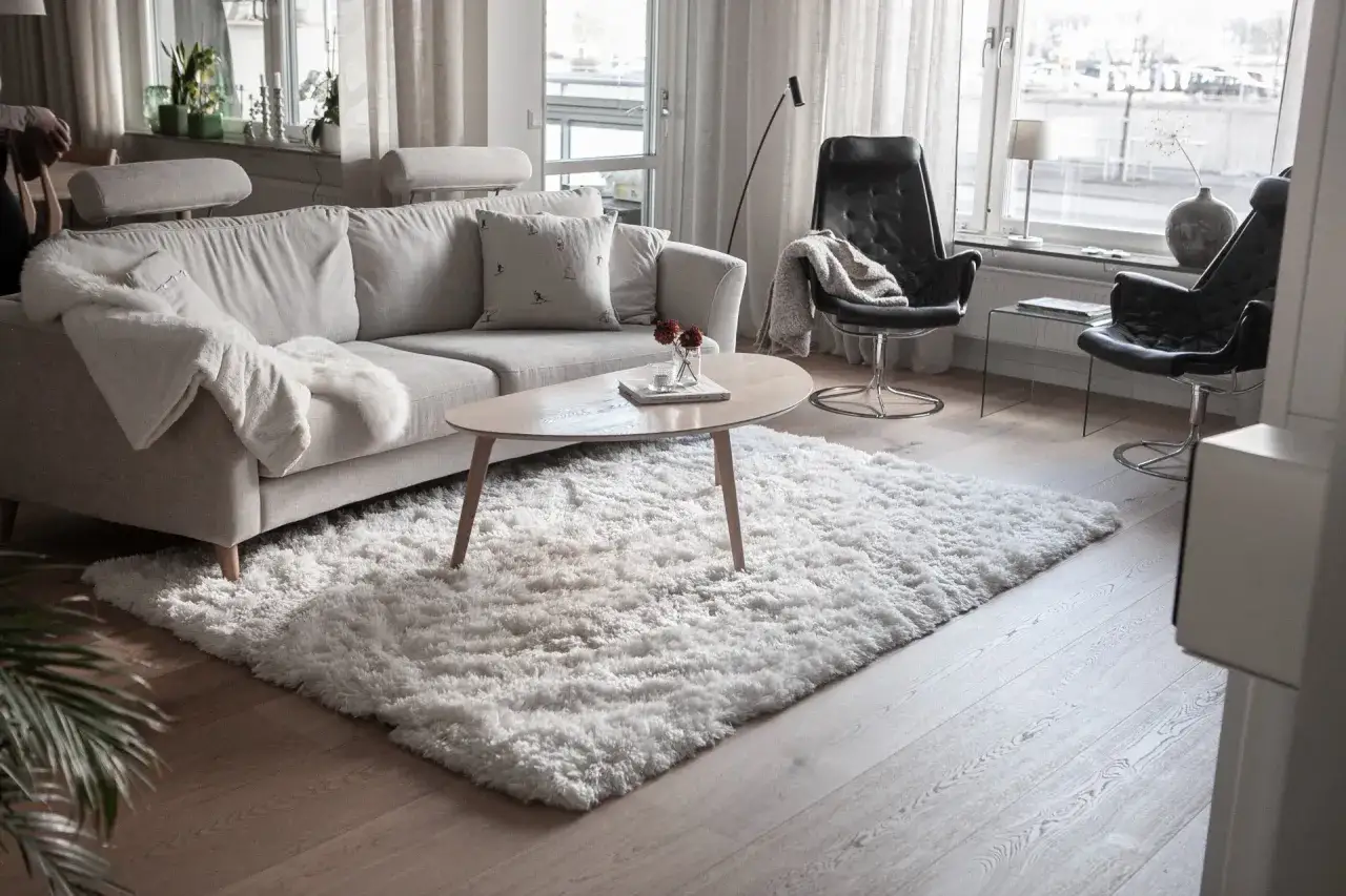 En fluffig, vit matta till grå soffa skapar en mysig känsla i vardagsrummet.