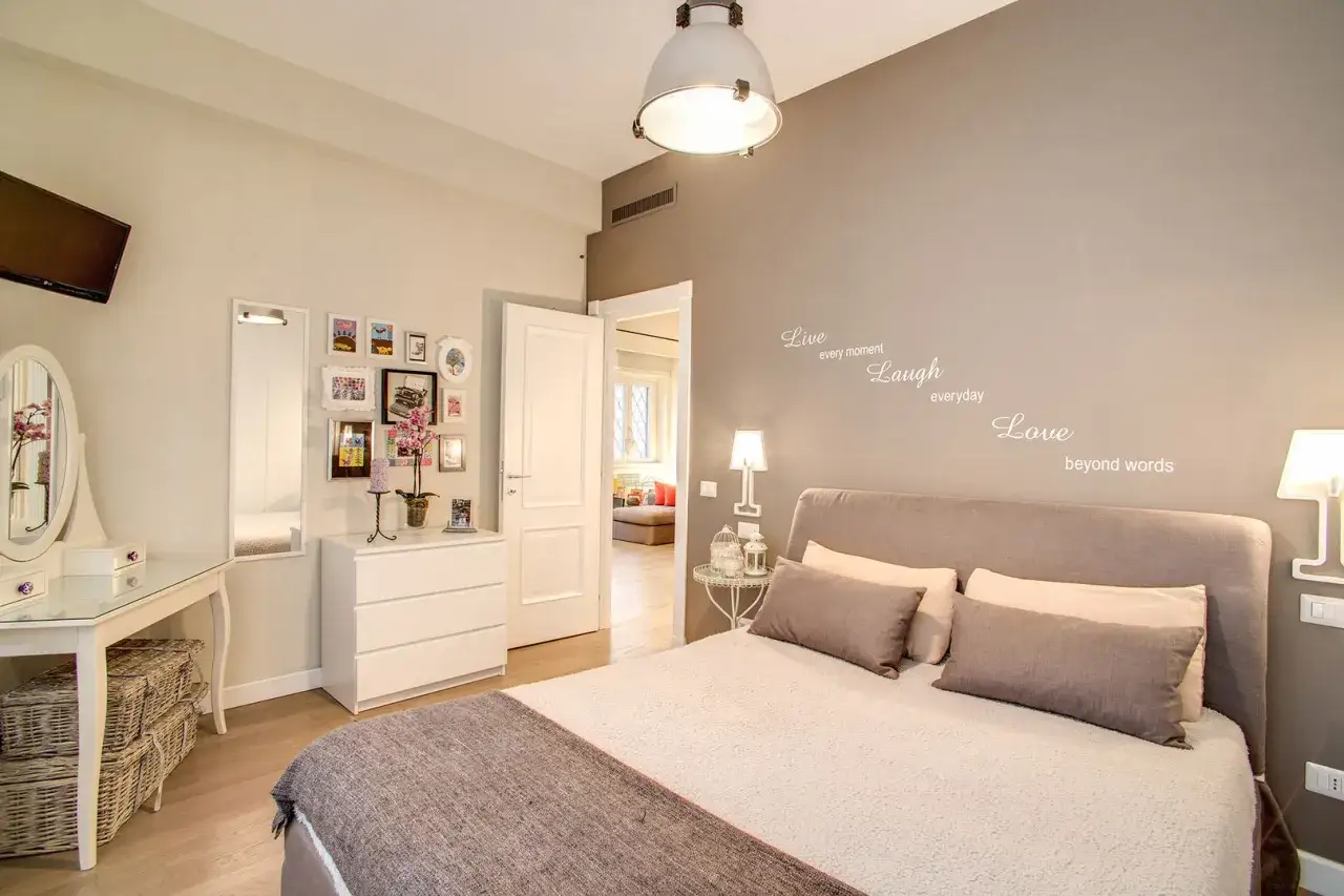 Camera da letto con idee originali: specchio, cassettiera, quadri, letto accogliente e citazioni motivazionali sul muro.