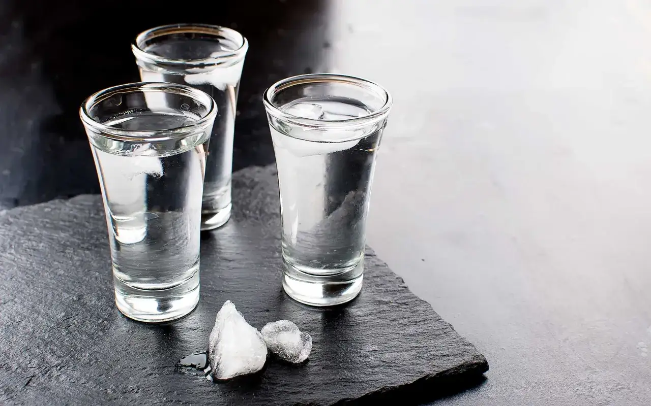 Drei Gläser mit Eiswürfeln, bereit für den Genuss. Die klare Flüssigkeit erinnert an die reine Vodka Herstellung.
