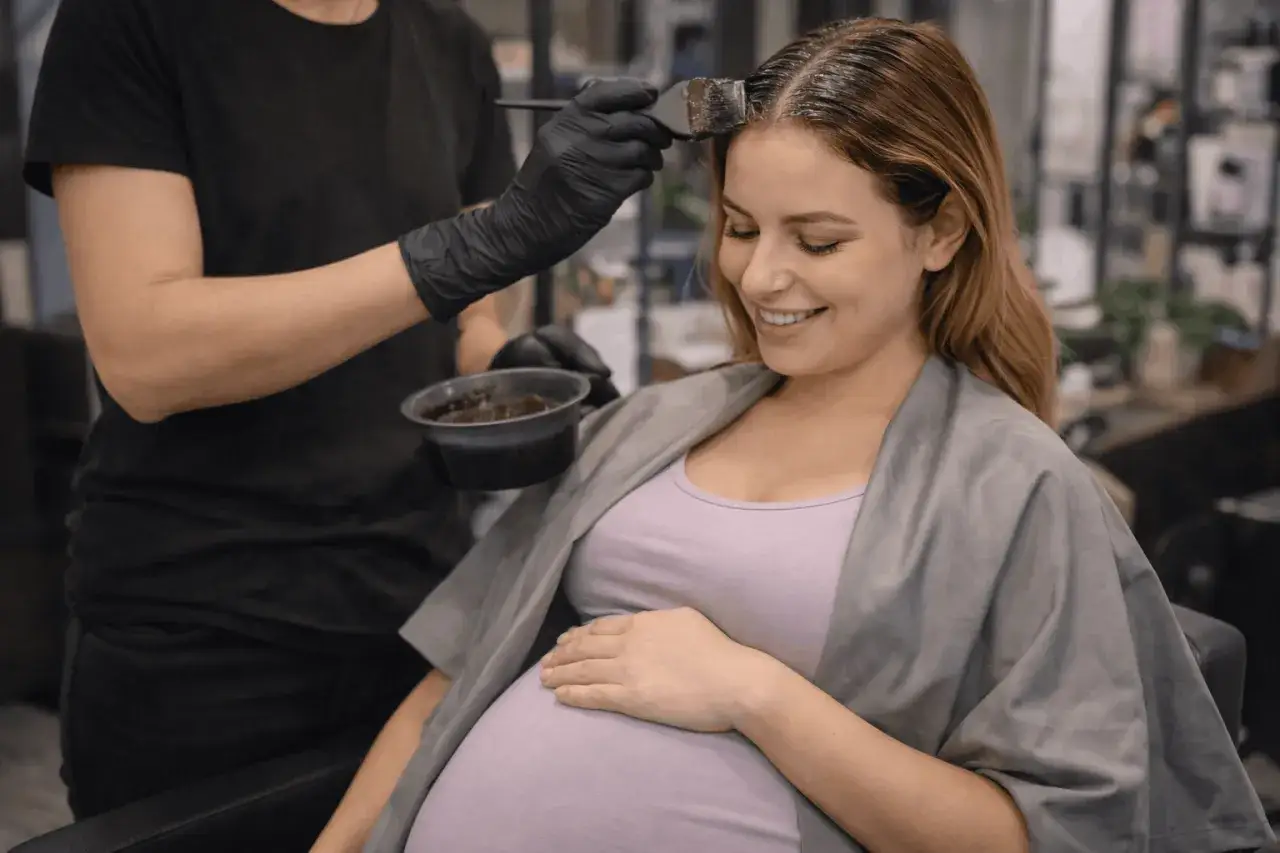 Donna incinta sorride mentre le viene applicata la tinta per capelli.