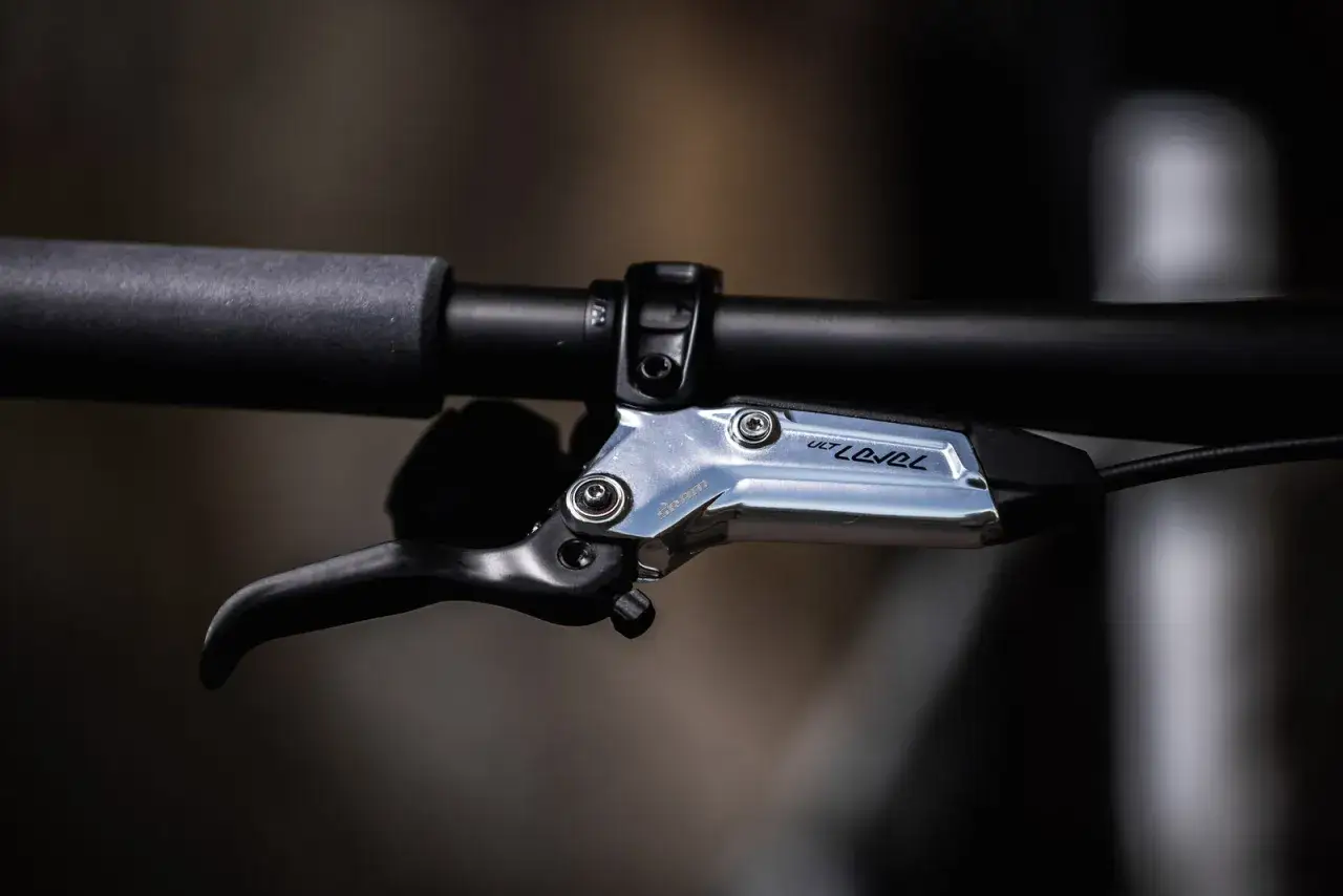 Close-up of a shiny SRAM Level Ultimate brakes lever on a bicycle handlebar, ready for the next trail adventure.