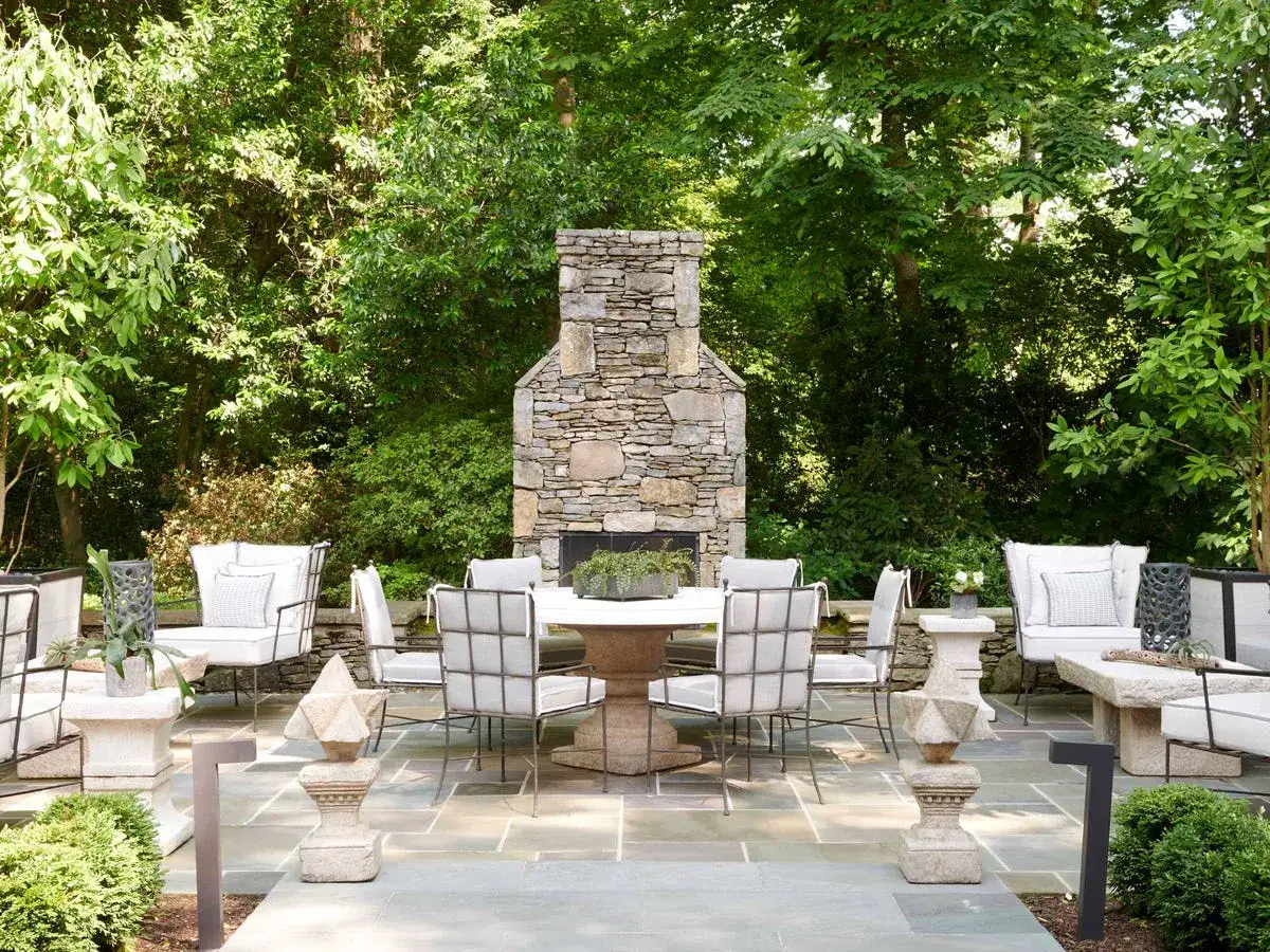 Un espace extérieur invitant avec cheminée en pierre, table et chaises pour une décoration véranda extérieur parfaite.