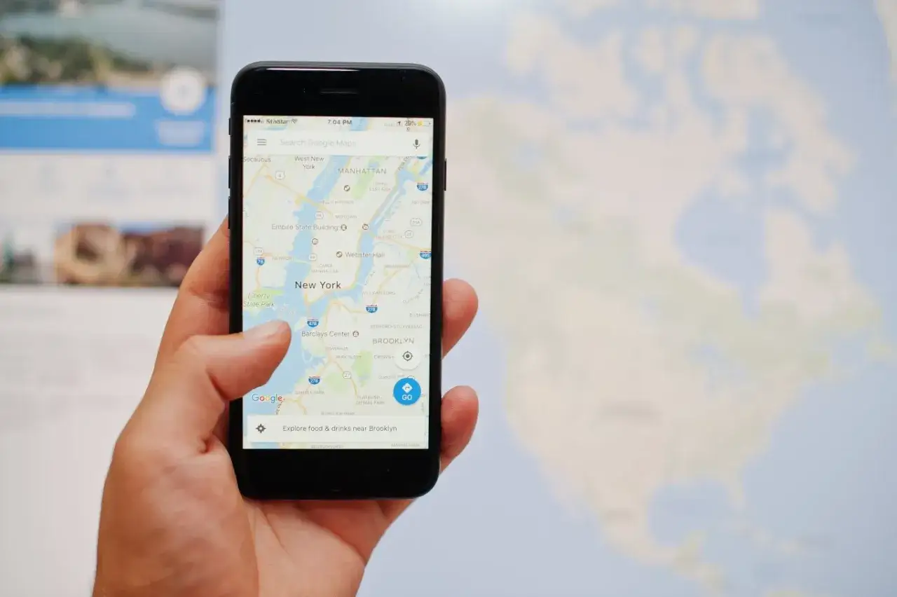 Dłoń trzyma smartfon z mapą Nowego Jorku. Dowiedz się, jak pobrać mapę Google offline, by podróżować bez dostępu do internetu.