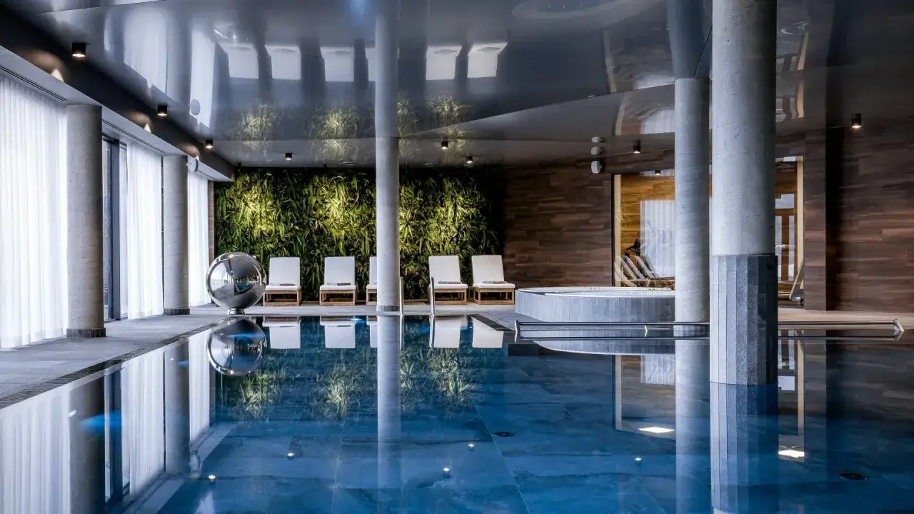 Relaks w basenie i jacuzzi podczas 2-dniowego pobytu w spa dla dwojga. Wygodne leżaki i zielona ściana tworzą atmosferę spokoju.