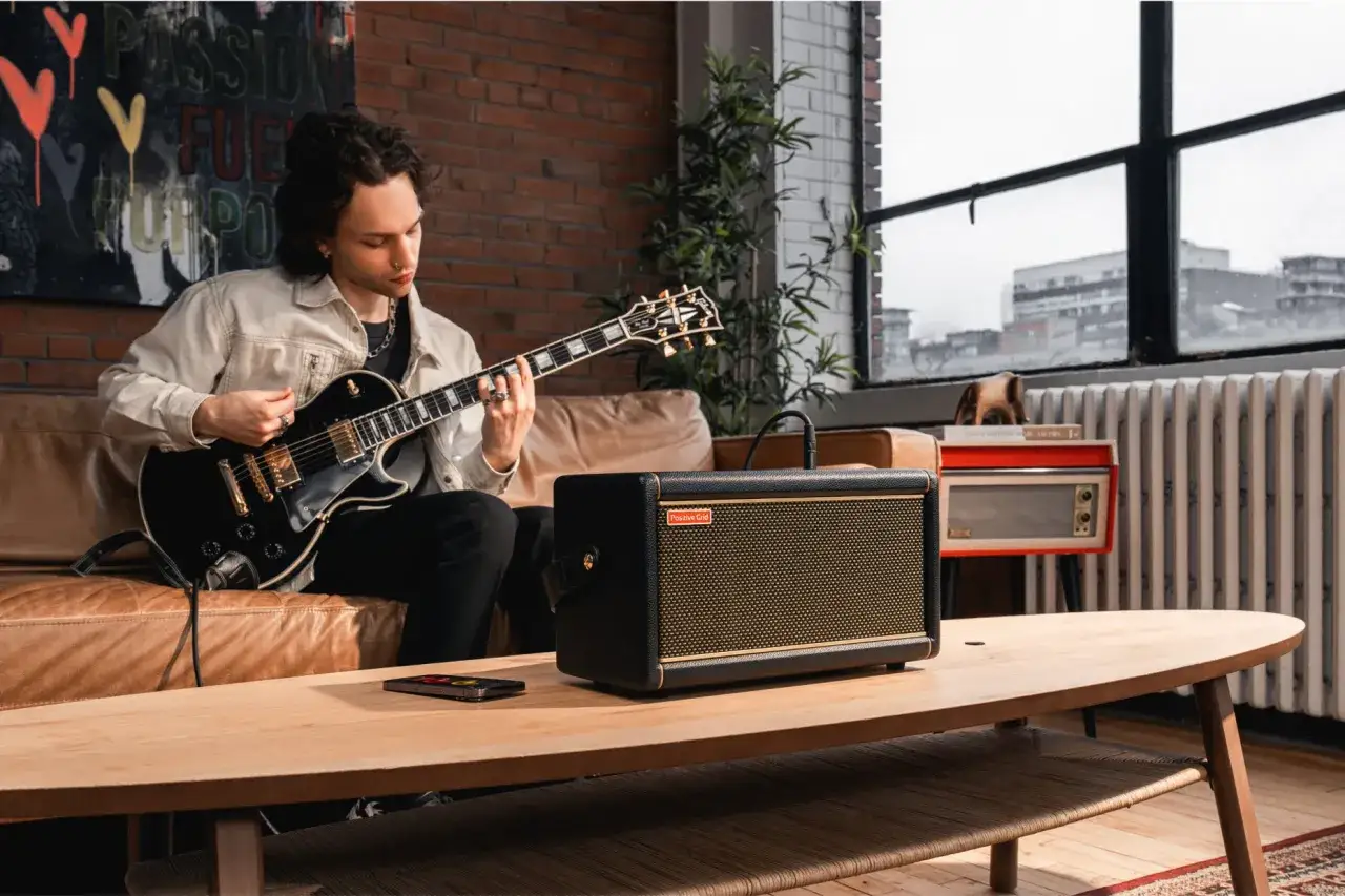 Mann spielt Gitarre, daneben ein Verstärker mit dem Logo