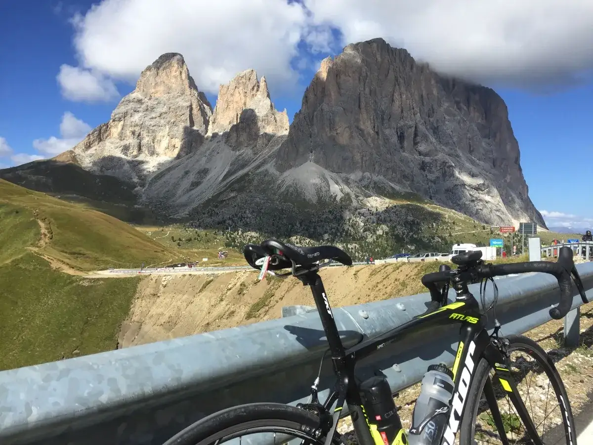Bicicletta nera pronta per affrontare la salita al **Passo Pordoi**, con le maestose vette delle Dolomiti sullo sfondo.