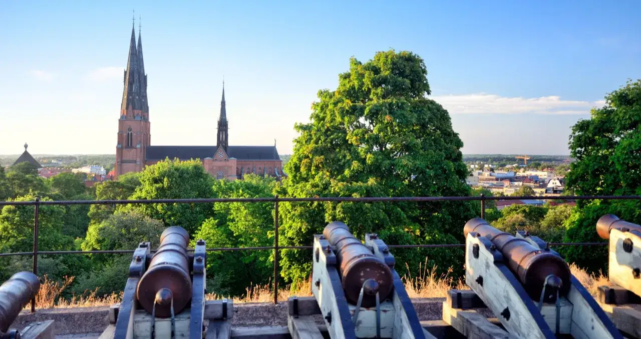 Gamla kanoner blickar ut över Uppsala domkyrka och stadens tak. En historisk vy att upplev uppsala ifrån.