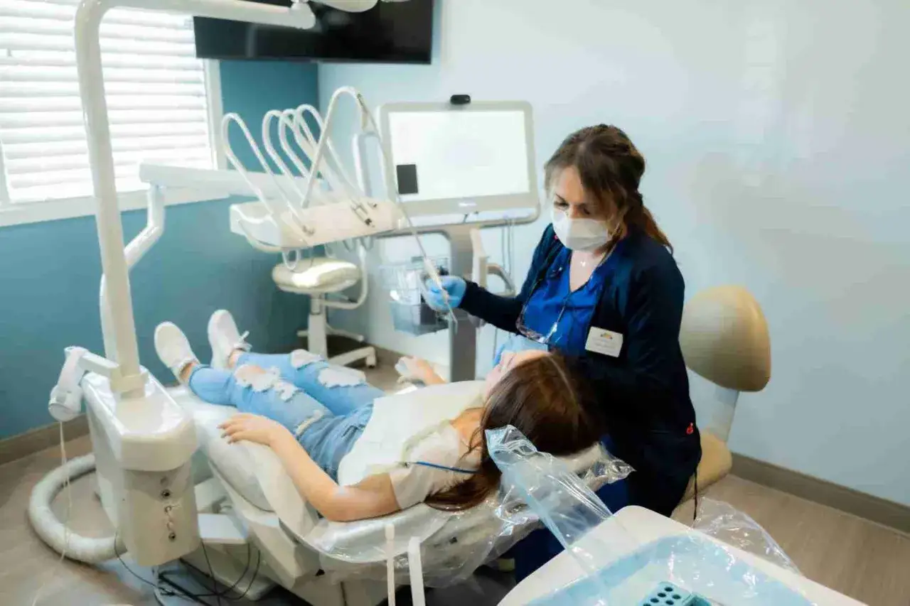 Dentystka wykonuje bonding zęba u młodej pacjentki w gabinecie stomatologicznym.