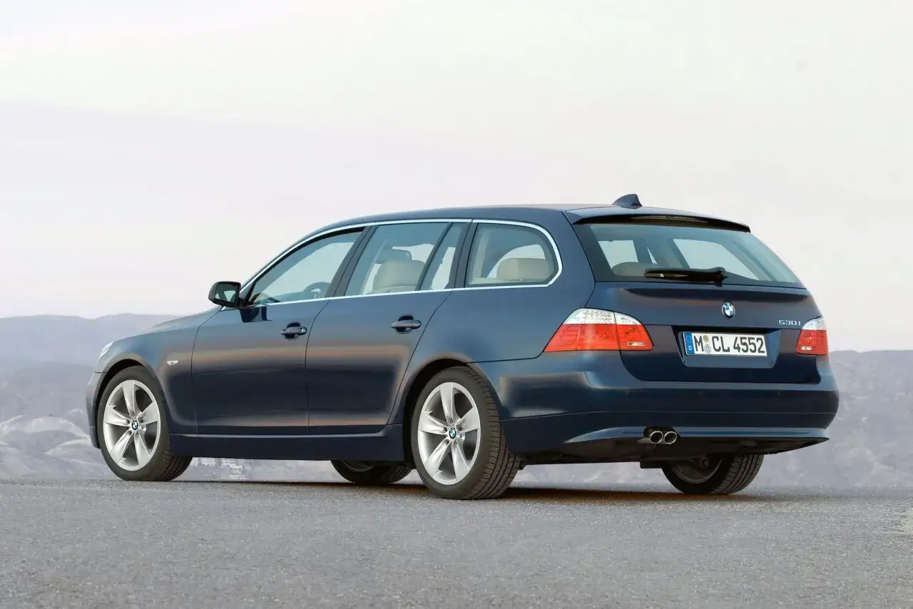 Granatowe e61 bmw kombi z jasnym wnętrzem, zaparkowane na pustkowiu.
