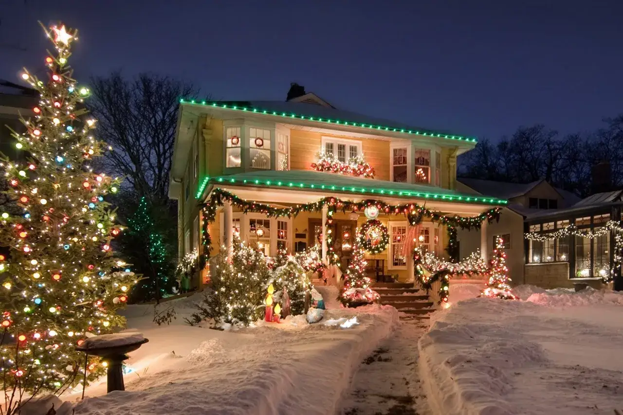 Casa decorata per il natale in inglese, con alberi illuminati e neve.