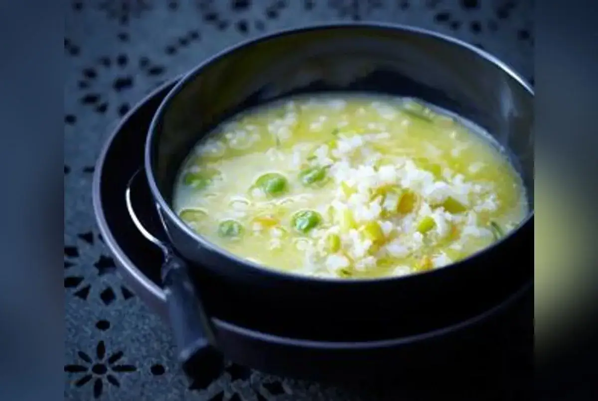 Un bol de soupe de riz cr&eacute;meuse avec des petits pois et des l&eacute;gumes verts. Un plat r&eacute;confortant et savoureux.