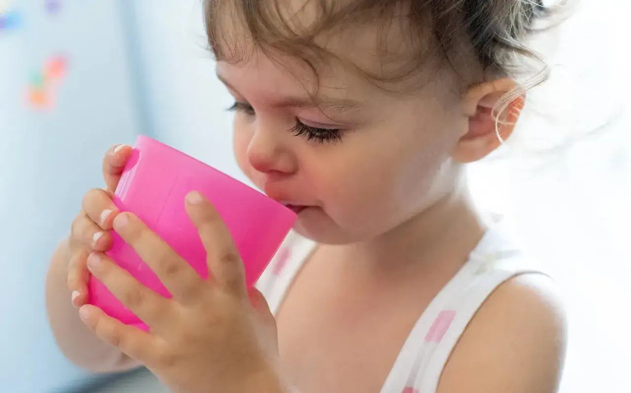 Kleines Baby trinkt aus pinkem Becher. Ab wann Tee Baby?