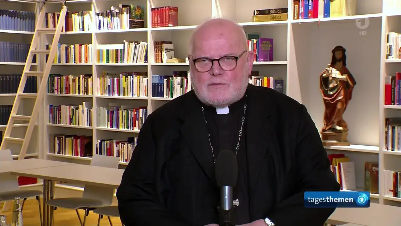 Reinhard Marx, Kardinal, spricht vor einem B&uuml;cherregal. Eine Jesus-Statue steht auf einem Regal.