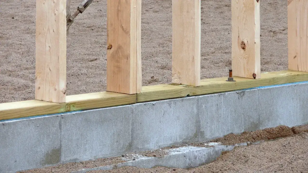 Solidny fundament pod dom szkieletowy, z drewnianymi słupkami osadzonymi na betonowej podmurówce.