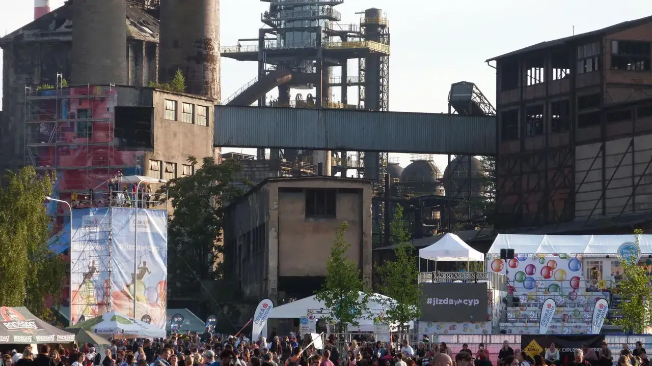 Bunte Banner und Zelte vor einer Industriekulisse beim Ostrava Festival. Menschenmassen genie&szlig;en die Atmosph&auml;re.