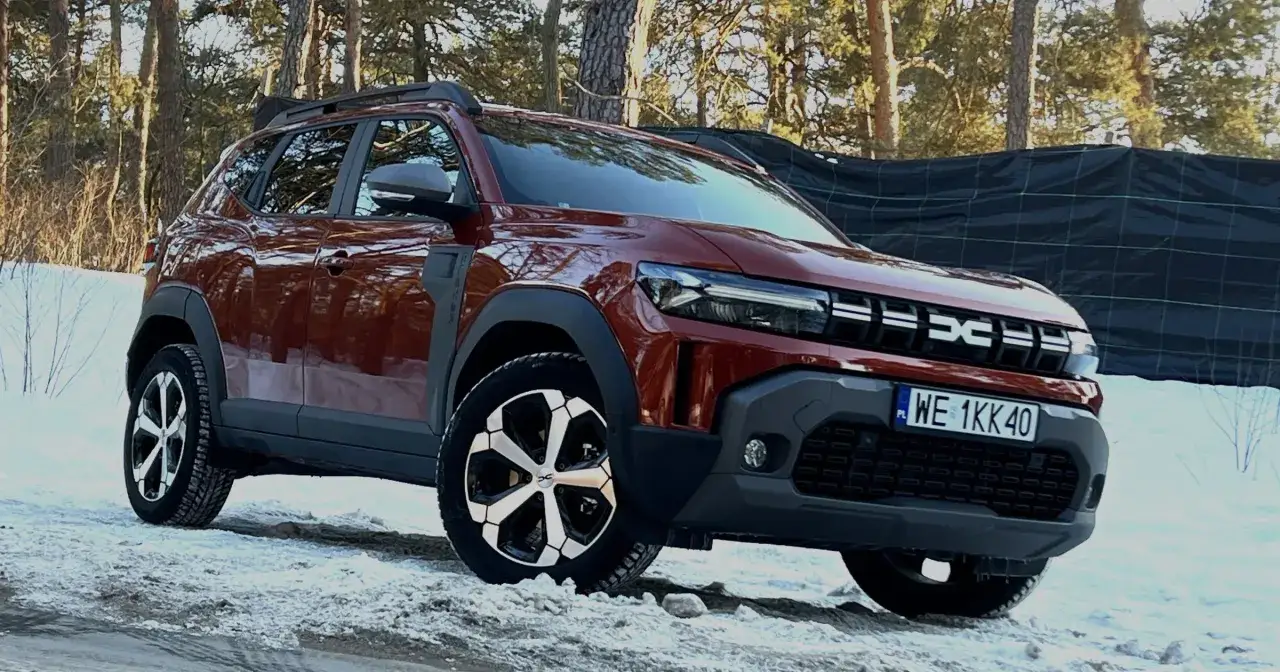 Czerwony, tani SUV Dacia Duster na śniegu, gotowy na zimowe wyzwania.