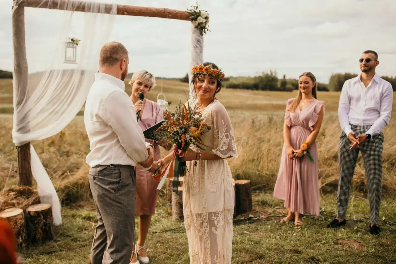 Para wielu os&oacute;b ślub humanistyczny jest ważny, bo celebruje miłość i więź. Panna młoda w wianku z kwiat&oacute;w trzyma bukiet, pan młody stoi obok.