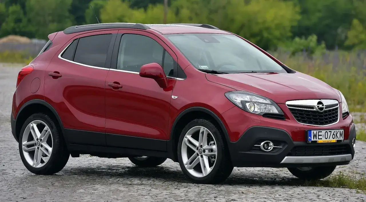 Czerwony Opel Mokka 2024 na kamienistej drodze, gotowy na przygodę.