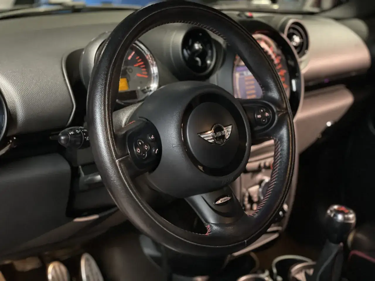Wnętrze mini paceman z kierownicą, deską rozdzielczą i dźwignią zmiany biegów.