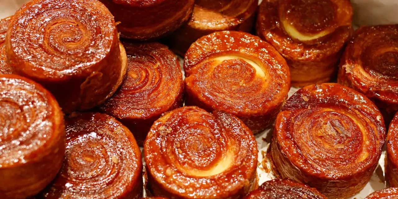 Gros plan sur des kouign amann brillants, leur signification réside dans leur caramel croustillant et leur pâte feuilletée.