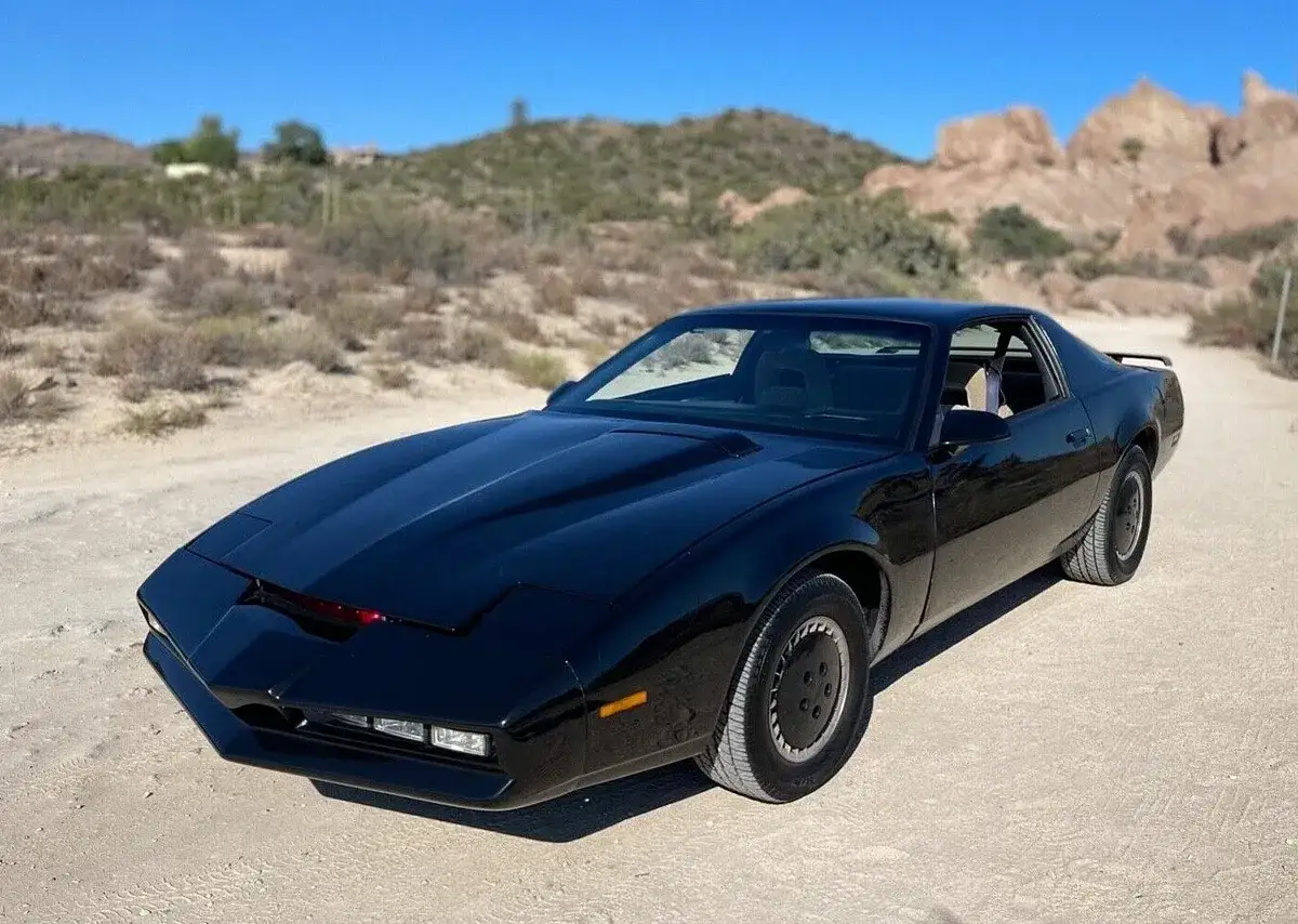 Svart Knight Rider bil parkerad p&aring; en grusv&auml;g i &ouml;kenlandskap.