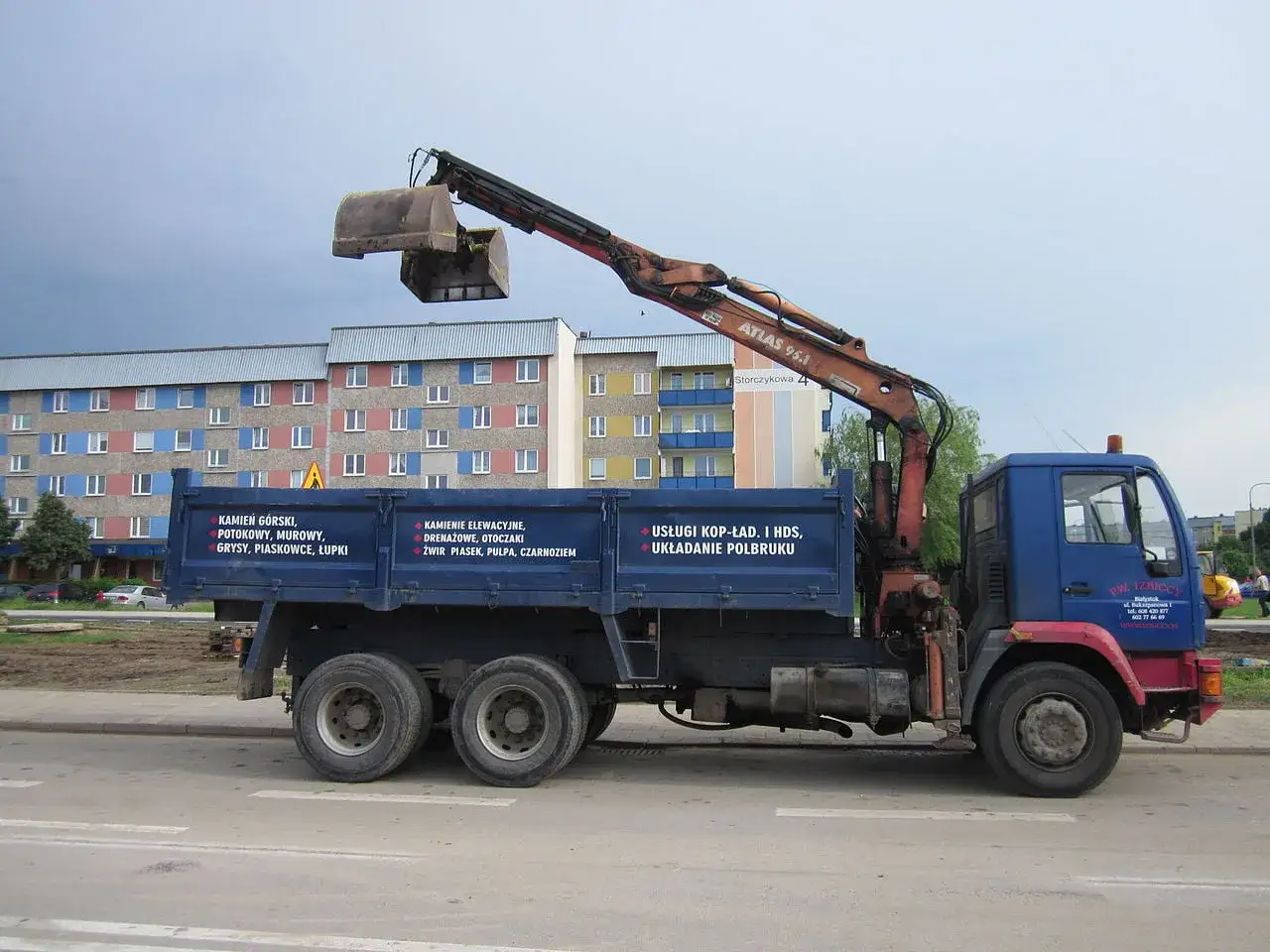 Ciężarówka z HDS-em, idealna do kursów HDS Toruń, rozładowuje materiały budowlane.