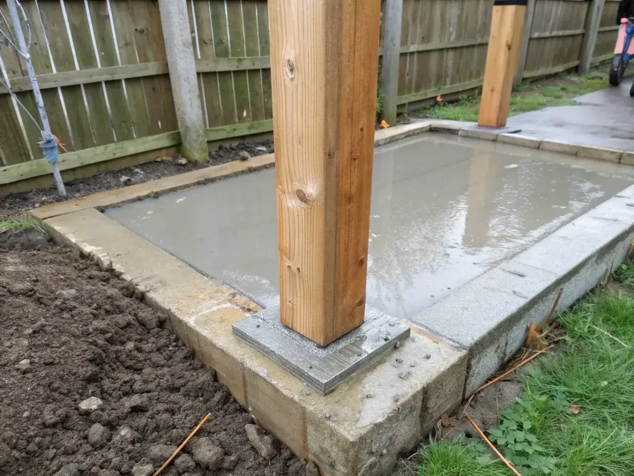 Grunden f&ouml;r att bygga staket &auml;r p&aring; plats. En tr&auml;stolpe st&aring;r stadigt p&aring; en betongplatta.