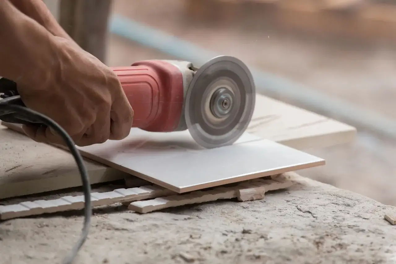 Hands carefully cutting porcelain tile with an angle grinder, creating a clean edge for a perfect fit.