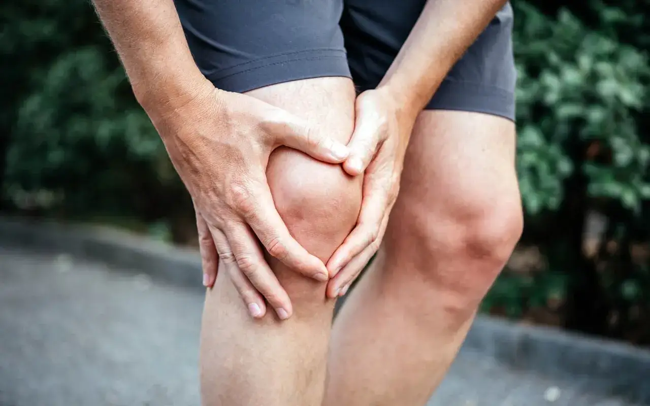 H&auml;nde umfassen schmerzendes Knie, deutet auf eine Distorsion Knie hin.